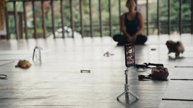 Smartphone recording yoga class with puppy
