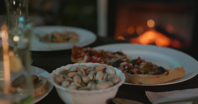Close-up Bowl with Pistachios on Table Near Fireplace. 4K 10-bit