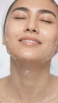 Young woman is washing her face with water