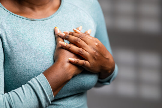 African woman experiencing chest pain or discomfort, holding hands over her heart
