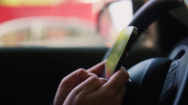 Female person texting on smartphone while sitting behind steering wheel, distracted driving concept, 4K