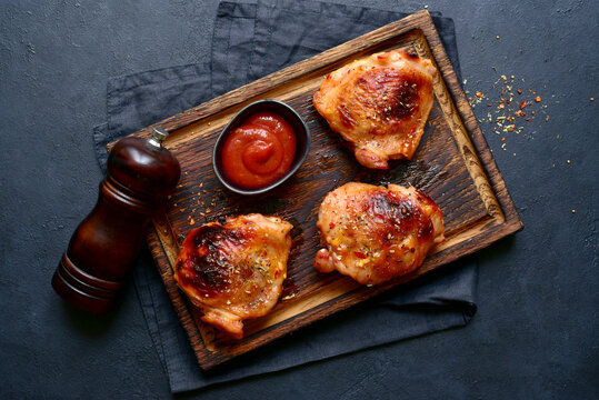 Roasted chicken thighs with ketchup . Top view with copy space.