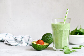 Fototapeta premium Detox avocado spinach smoothie in a tall glass. Top view with copy space.