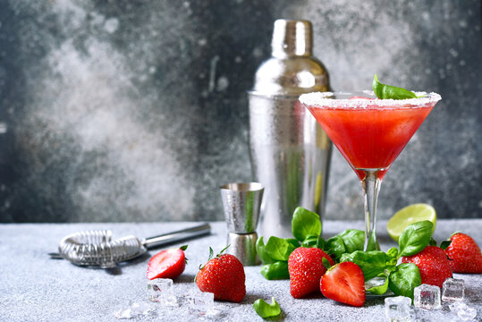 Cold summer strawberry cocktail with lemon and basil in a martini glasses .