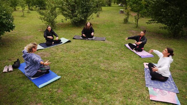 Yoga class in a women's circle on mats among the trees in windy weather. High quality 4k footage