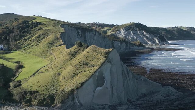 Majestic aerial view of the breathtaking Sakoneta beach, revealing its unique flysch rock formations extending into the ocean along the lush green coastline of the Basque Country in Spain