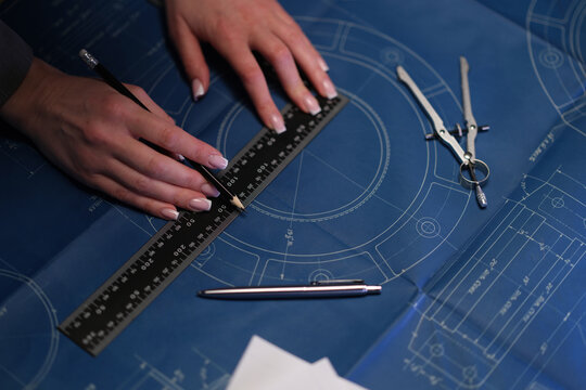 Hands drafting blueprint with ruler, closeup showing architect at work, compass and pencil marking concentric circles