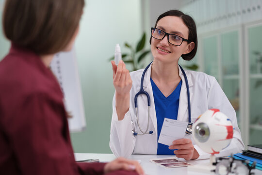 Ophthalmologist explaining eye drop usage and eye model, demonstrating instillation technique, vision care counseling