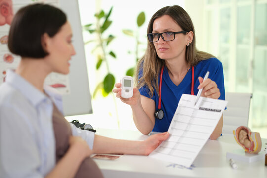 Pregnant woman consulting obstetrician in clinic, doctor holding chart and explaining prenatal plan, calm bright exam room,