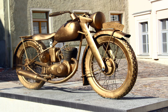 Zschopau, Germany - April 24, 2026: Golden sculpture of a 1922 DKW-style motorcycle commemorating MZ Zschopau, Germany&rsquo;s historic birthplace of mass-produced motorcycles