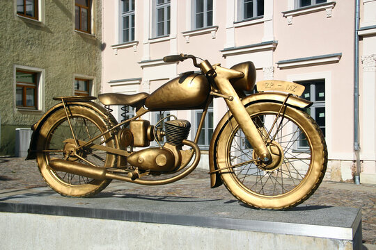 Zschopau, Germany - April 24, 2026: Golden sculpture of a 1922 DKW-style motorcycle commemorating MZ Zschopau, Germany&rsquo;s historic birthplace of mass-produced motorcycles