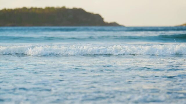 Gentle turquoise wave crest forming near shoreline in clear coastal waters