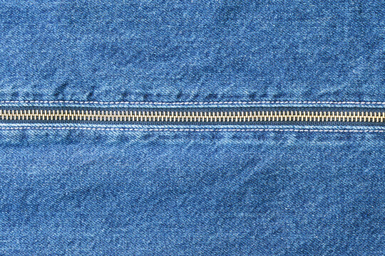 Denim zipper repair. Closeup of denim with zipper. Tailor repairing denim pocket under studio lighting. Indigo denim fabric with brass hardware and textured weave details