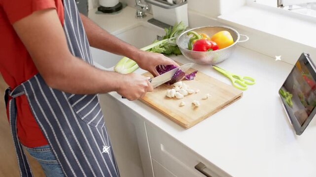 Vertical video: Cook placing board slicing cabbage, garlic, using tablet teal sweeping across hands