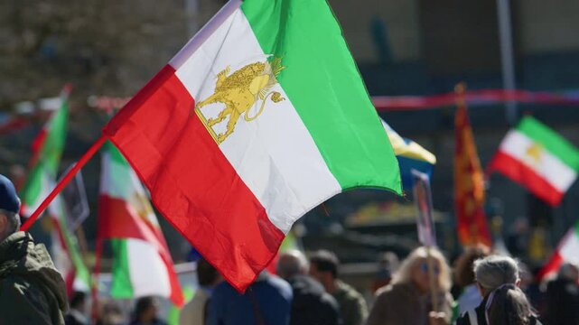 Crowd holding Iranian flags during demonstration with blurred participants background