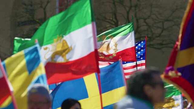 Multiple international flags including Iran Sweden and USA at public rally