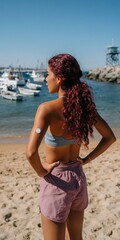Fototapeta premium Young woman standing at marina looking out over boats