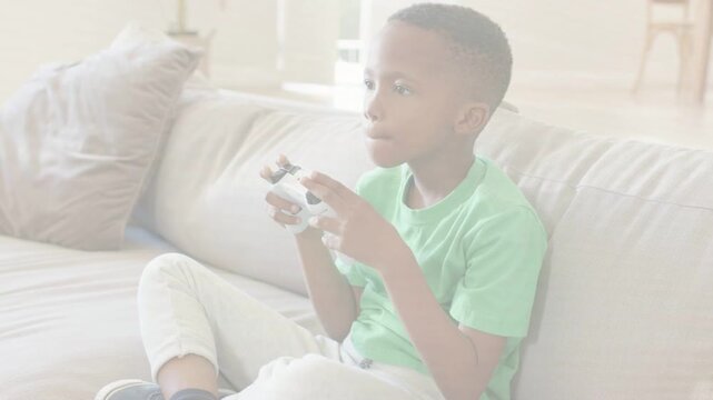 Boy holding white controller on couch, leaning in as onscreen game intensifying, following action