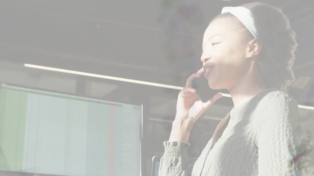 Mid adult woman answering phone, listening and smiling while handling business call by monitor
