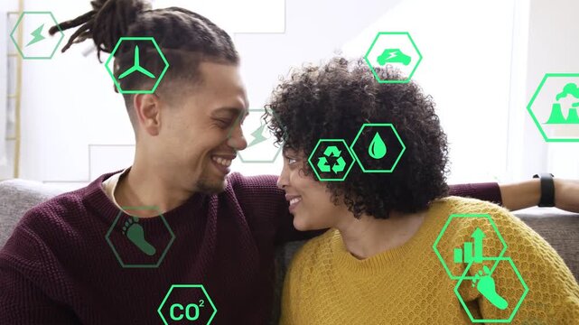 Couple on sofa holding hands leaning touching heads as green hexes floating over faces sharing love