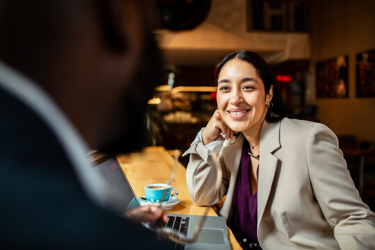 Smiling businesswoman meeting with colleague at cafe