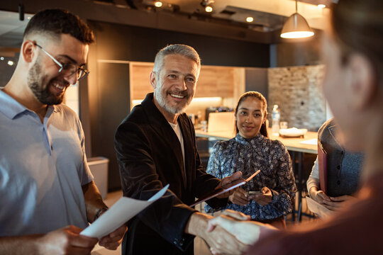 Smiling business team welcoming new colleague in modern office