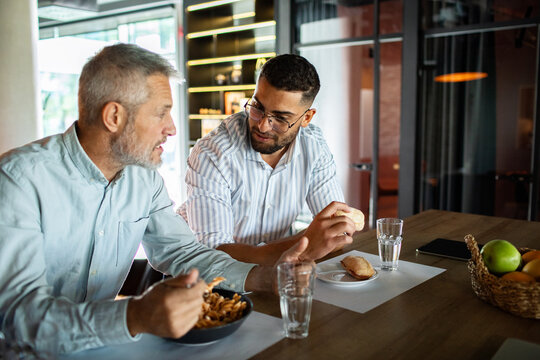 Two coworkers share lunch and conversation in a modern office break room