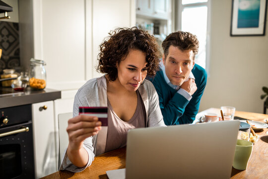 Couple shopping online with credit card at kitchen table