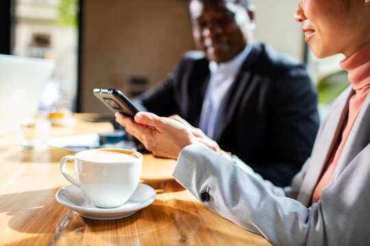 Coworkers discussing business on smartphone at cafe