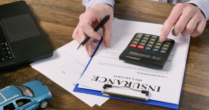 Man agent counts monthly premium for car protection policy at desk closeup. Professional manager works with financial papers and contract in bureau office