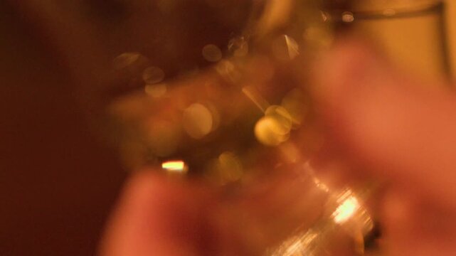 Close up motion of golden whiskey swirling in a glencairn glass, hand holding glass to show amber liquid, cinematic footage.