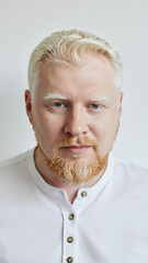 Obraz premium A serious man portrait with blonde hair and a beard wearing a white shirt in a studio.