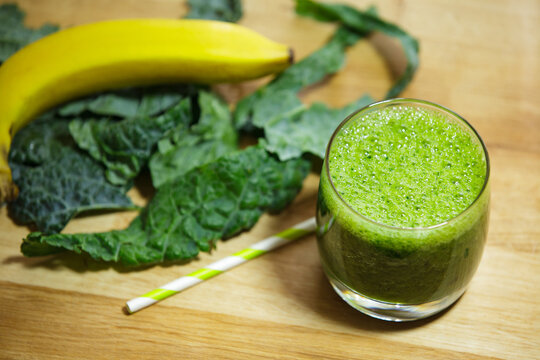 Glass of Nutritious Green Smoothie with Kale and Banana on Wooden Table