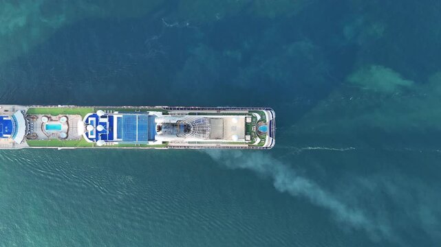 large luxury cruise ship sailing across a vast turquoise ocean. Concept of luxury maritime travel, ocean vacation, and bird's-eye perspective of tropical tourism.