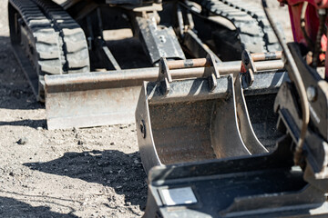 Two steel excavator buckets and a metal dozer blade resting on a construction site ground, representing heavy duty engineering equipment and earthmoving maintenance © K