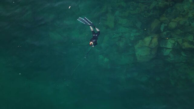 Aerial view of the spearfisherman hunting in the sea. Aerial top down view of the hunter in the water