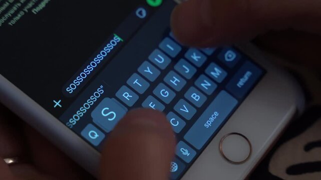Hands of a person typing an urgent message on a smartphone screen, showing the progression of text input with visible keyboard and illuminated display in a cozy indoor setting