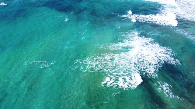 Top down aerial view of waves breaking into white foam, abstract patterns and textures of moving water