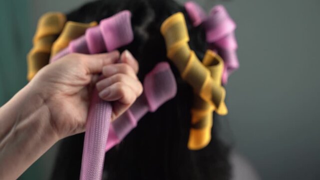 Hairdresser applying colorful perm rollers to a girls hair
