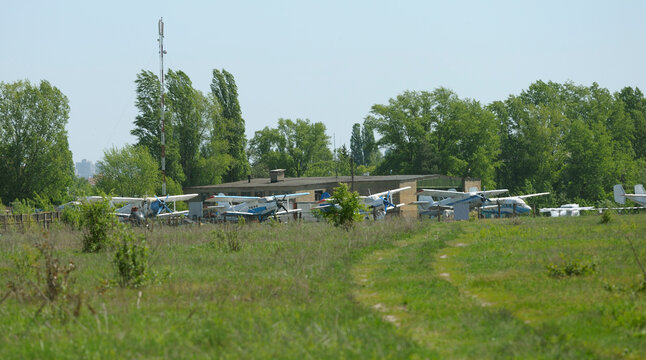 Antonov An-2 light aircraft parked at a grassy airfield under a clear sky