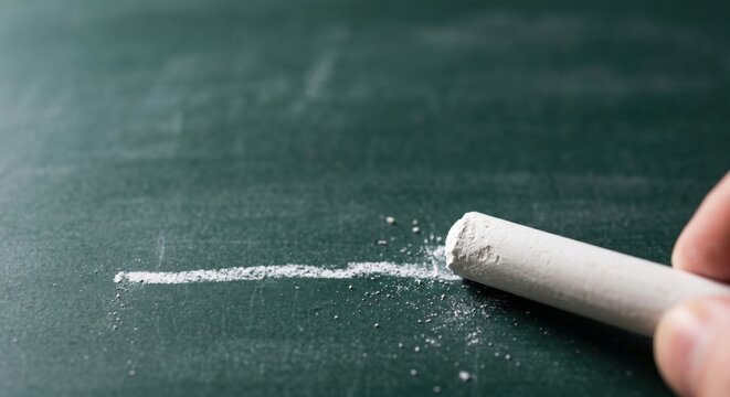 Chalk drawing a line on green chalkboard with white chalk