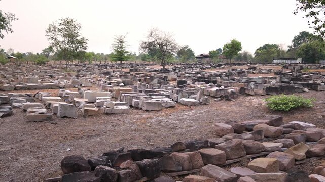 Restoration site of ancient Khmer ruins with sandstone blocks organized on the ground, Champasak, Southeast Asia