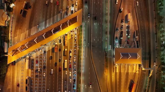 Aerial view of traffic on highways and toll booths at night.