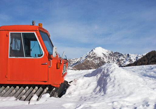tracked snowplough parked in front of piled snow 