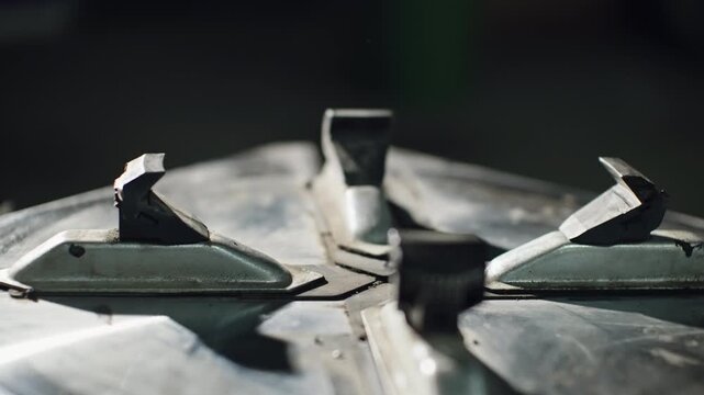 Close-up of an industrial metal chuck with four movable jaws on a workshop machine, showcasing weathered steel, mechanical wear, and precise clamping components in shallow focus