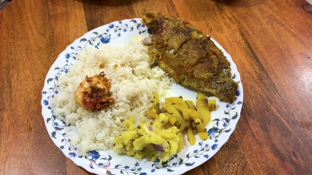 traditional home cooked indian food with rice fish fry and sabzi