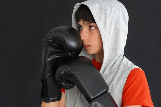 boy with black boxing gloves, a red t-shirt and a gray hoodie