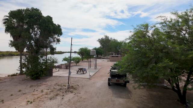 Aerial view shows SUV with a teardrop camper at a campsite in Baja California along a river.