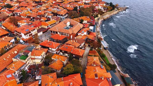 Footage over the red roofs of villas densely built in the urban landscape of Nessebar, Bulgaria. The Black Sea waves slowly roll to the coast.