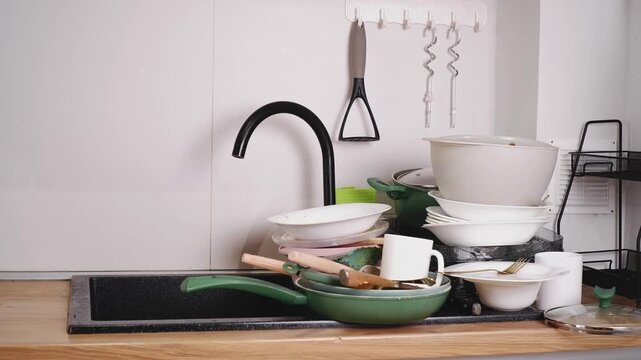 Pile of dirty dishes with food leftovers in the kitchen sink ready for washing after a party